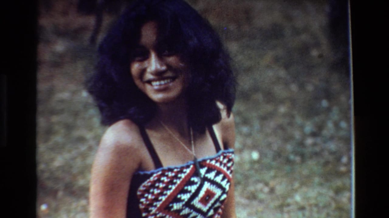 Smiling woman in a patterned halter top standing outdoors against a blurred green background.