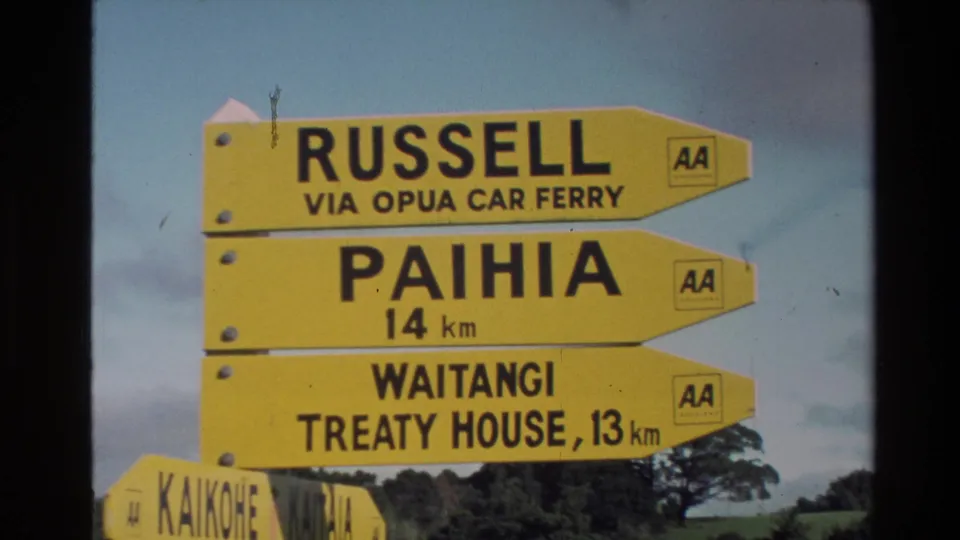 Clear New Zealand road signs point toward Russell, Paihia, and Waitangi Treaty House, with AA logos on the signboards.