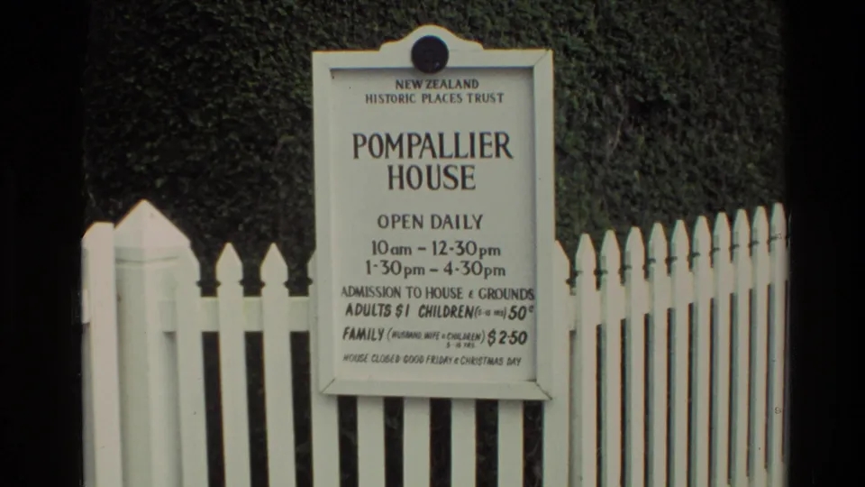 1981 New Zealand 8mm frame showing the Pompallier House admission sign mounted by a white picket fence.