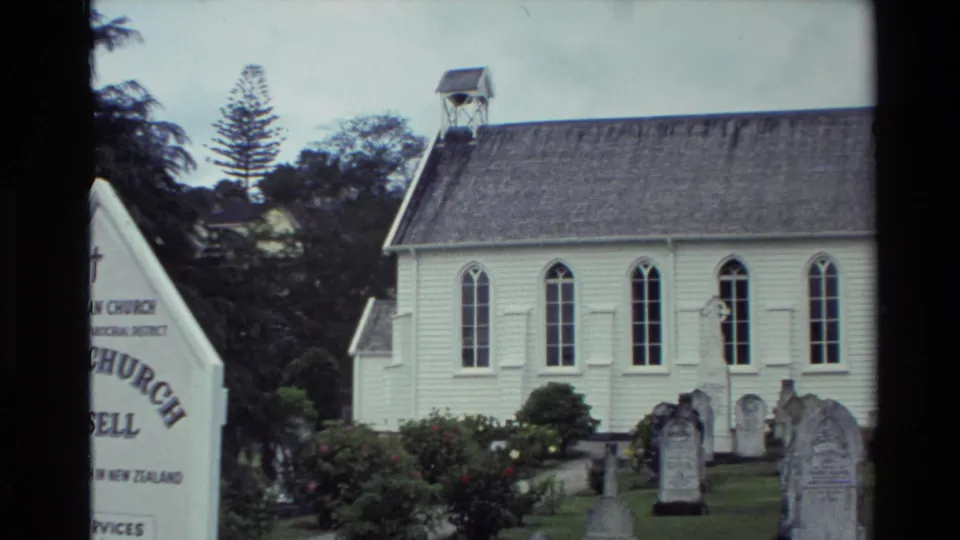 Visitor-shot 1981 view of Christ Church Russell with its white facade, arched windows, cemetery headstones, and partial entrance sign.