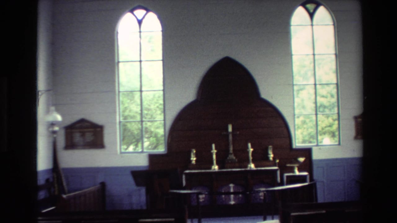 1981 New Zealand 8mm view of a church altar area, with bright arched windows, a dark carved backdrop, a central cross, and candlesticks.