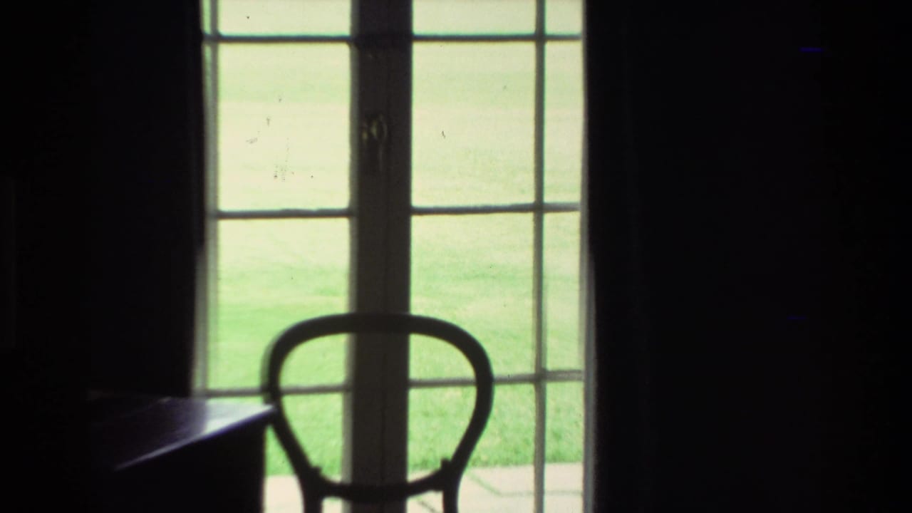 1981 New Zealand 8mm frame with a chair silhouette in front of French doors opening onto bright grass.