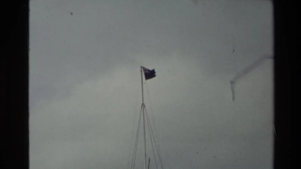 1981 New Zealand 8mm frame showing a flag on a tall pole in wind against a pale overcast sky.