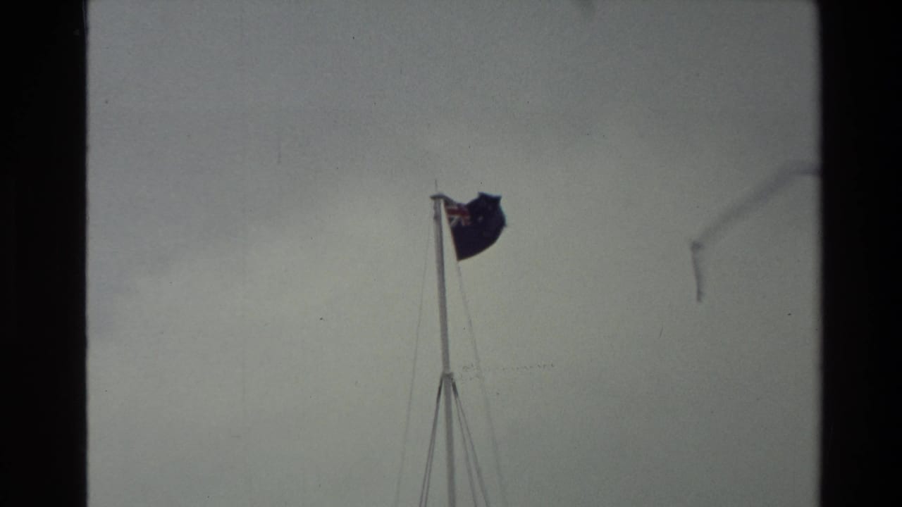 Flag on a pole seen through faded 8mm film with a grey sky.