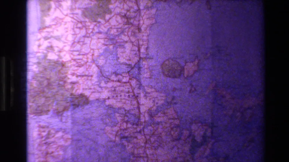 1981 New Zealand travel footage shows a printed map with red lines and geographic outlines, softened by grain and color shift.