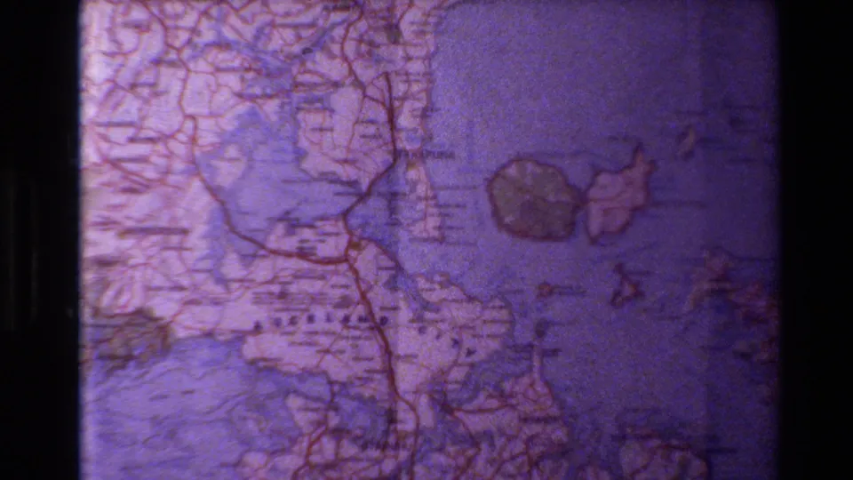 A closer 1981 home-movie view of the New Zealand map shows the Auckland area with roads, labels, water, and island shapes.
