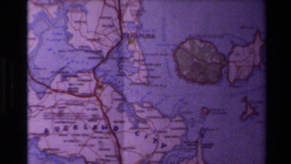 The final frame is a tight 8mm close-up on the Auckland-area roadmap, with printed labels, red roads, blue water, and island outlines.