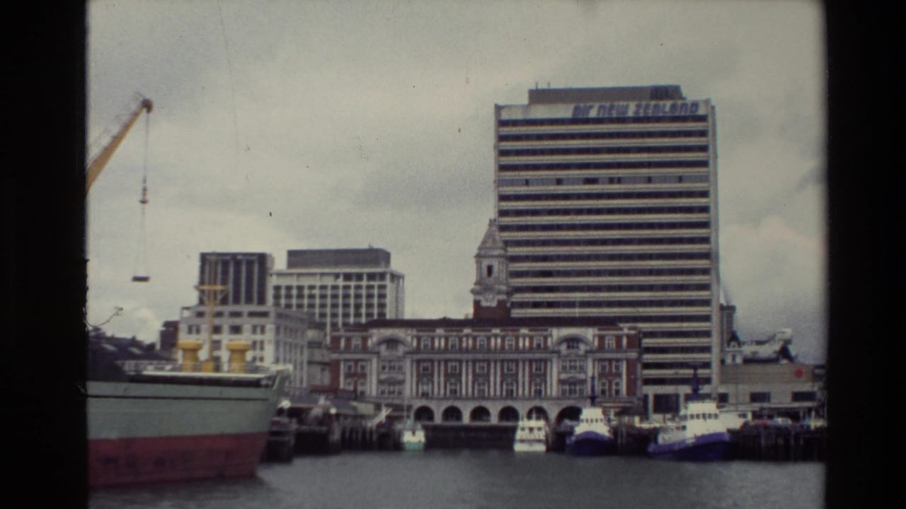 Waterfront buildings behind docked vessels, with a tall Air New Zealand office block and cranes visible.