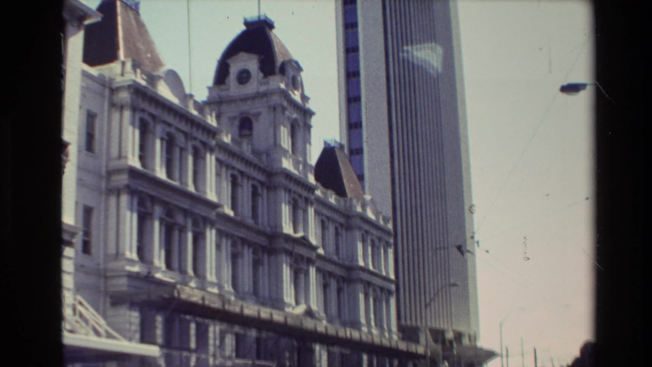 Closer 1981 New Zealand view of the older multi-story facade with a modern vertical tower rising behind it.