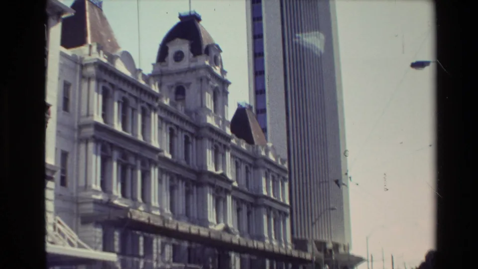 Closer 1981 New Zealand view of the older multi-story facade with a modern vertical tower rising behind it.