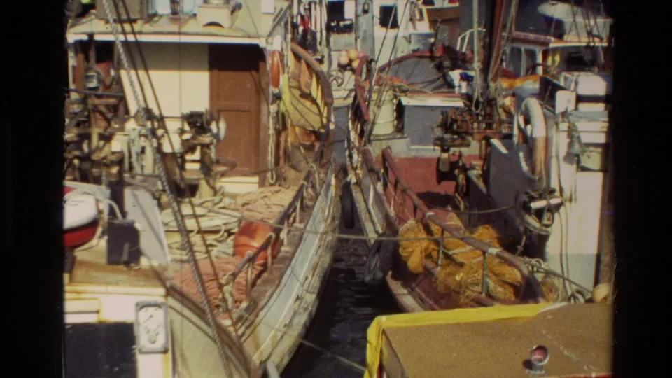 1981 New Zealand 8mm frame showing docked fishing boats packed with ropes, netting, railings, and working deck equipment.