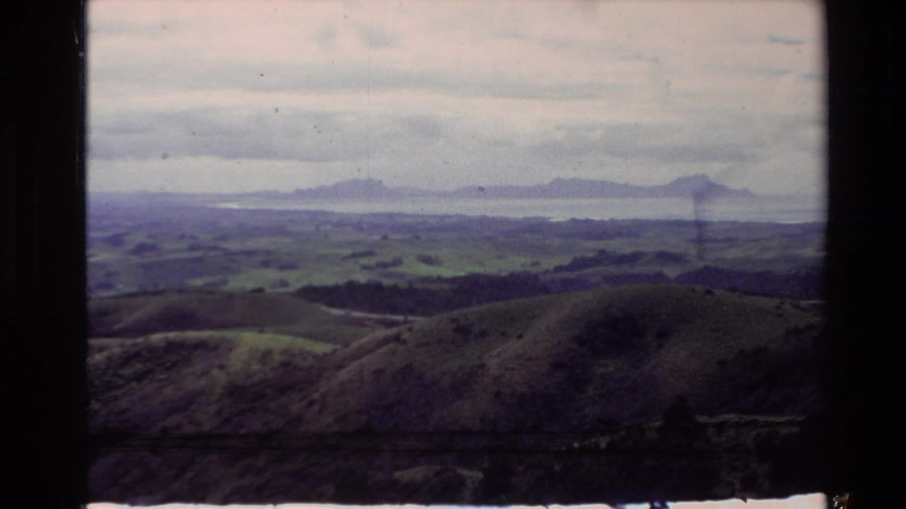 Pastoral hills and distant mountain range beneath layered clouds.