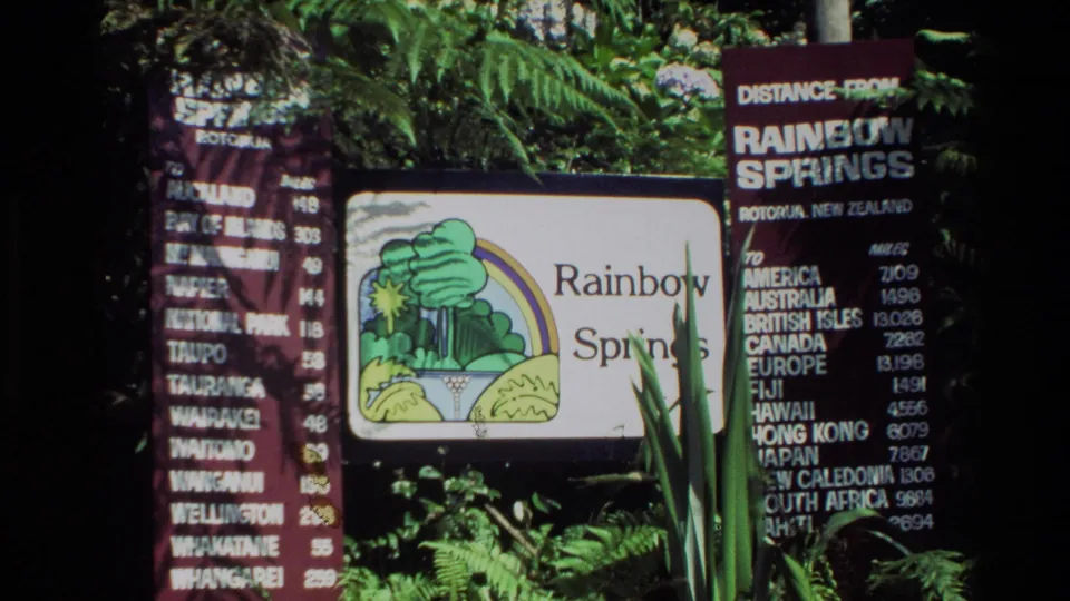 1981 New Zealand 8mm frame of Rainbow Springs signage near ferns and a board listing distances.