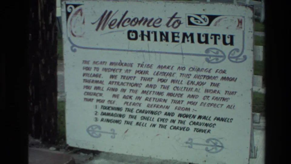 Outdoor Ohinemutu welcome sign with decorative border and visitor guidance text in 1981 New Zealand footage.