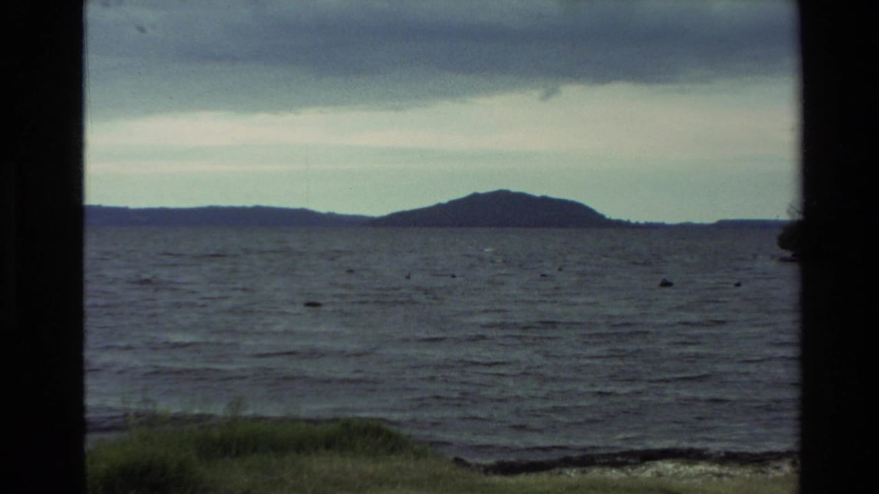 Wide view across a lake with low hills on the far shore and dark vertical frame edges.