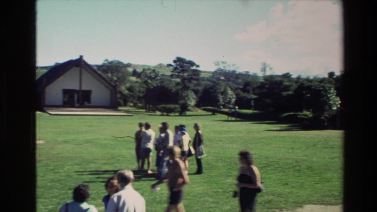 Visitors gathered on a green lawn near a white gabled building.