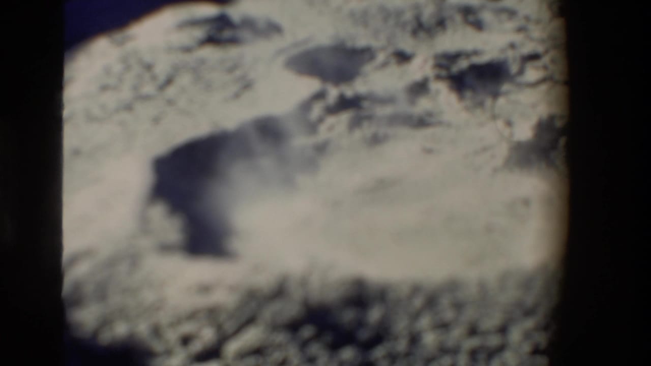 1981 New Zealand 8mm frame showing a soft-focused geothermal surface with pale mineral ground, dark openings, and low steam.