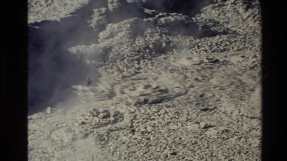 1981 New Zealand 8mm frame showing textured geothermal mud or mineral deposits, a small dark vent, and drifting steam.
