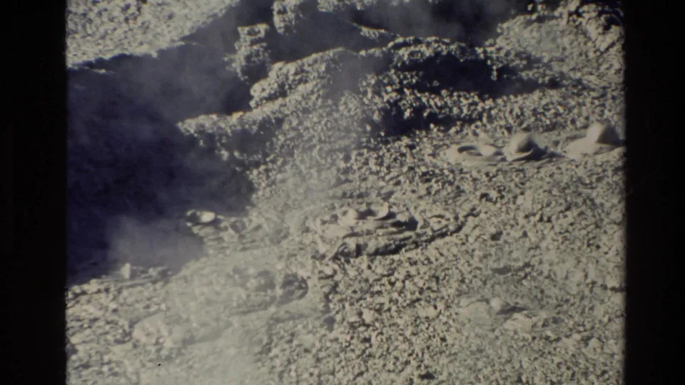 1981 New Zealand 8mm frame with rough geothermal terrain, pale mineral crust, small vent openings, and steam moving through the lower frame.
