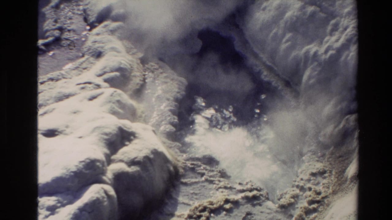 1981 New Zealand 8mm frame showing a close view of steam and boiling water erupting among pale rocky formations.