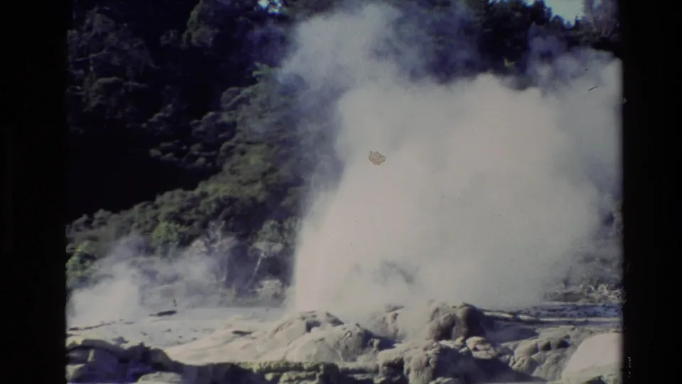 1981 New Zealand 8mm frame where a dense white steam cloud covers much of the geyser vent and surrounding mineral ground.