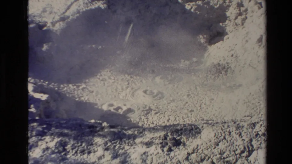 1981 New Zealand 8mm frame showing pale mineral ground and remaining steam across a geothermal basin after the geyser burst.