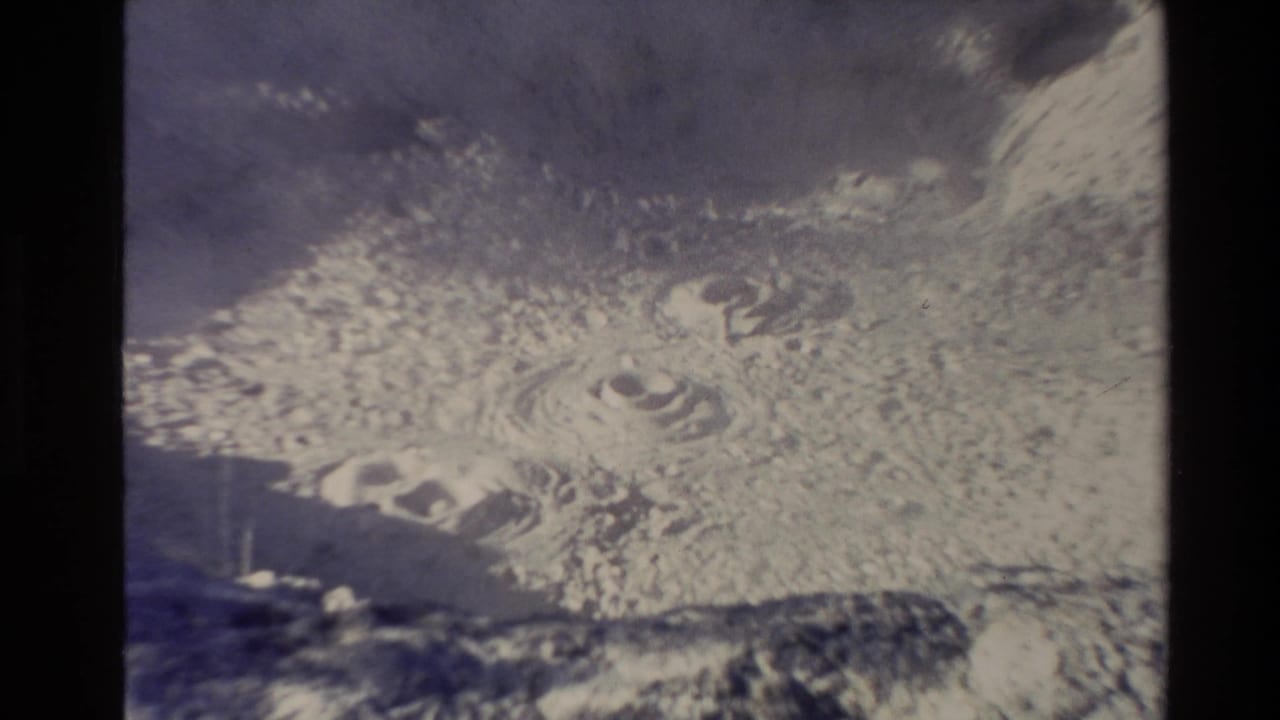 1981 New Zealand home-movie frame showing boiling volcanic mud with ripples, bubbles, haze, and small-gauge film edges.