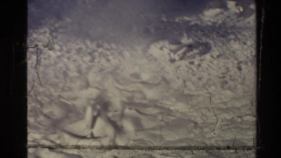 Archival home-movie frame of New Zealand geothermal mud bubbling in soft focus, with film scratches, gate edges, and uneven exposure.