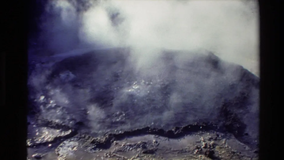 1981 New Zealand 8mm frame showing steam rising from a dark geothermal surface, with high contrast and visible film texture.