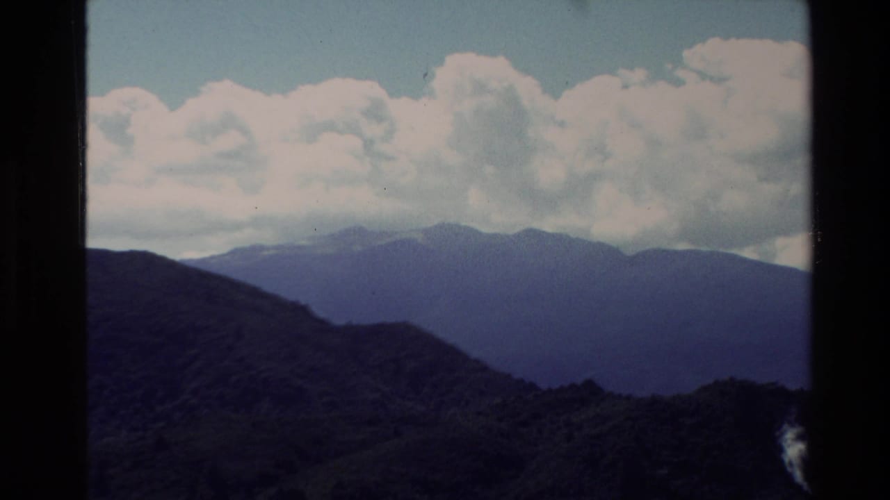 1981 New Zealand 8mm frame showing layered mountain ridges under a clouded sky, with dark film edges visible.
