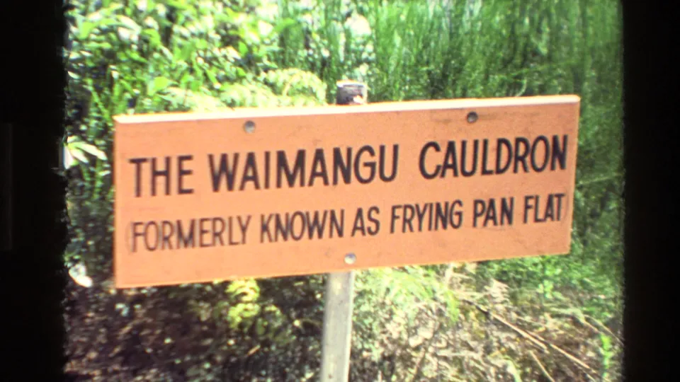 1981 New Zealand 8mm frame with a wooden sign identifying The Waimangu Cauldron, formerly known as Frying Pan Flat.