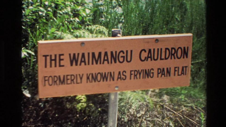 New Zealand 1981 home-movie frame showing the Waimangu Cauldron sign with surrounding plants and soft 8mm color.