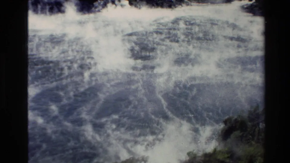 The 1981 home-movie frame shows a broad wave break and foam spreading through blue-green coastal water.