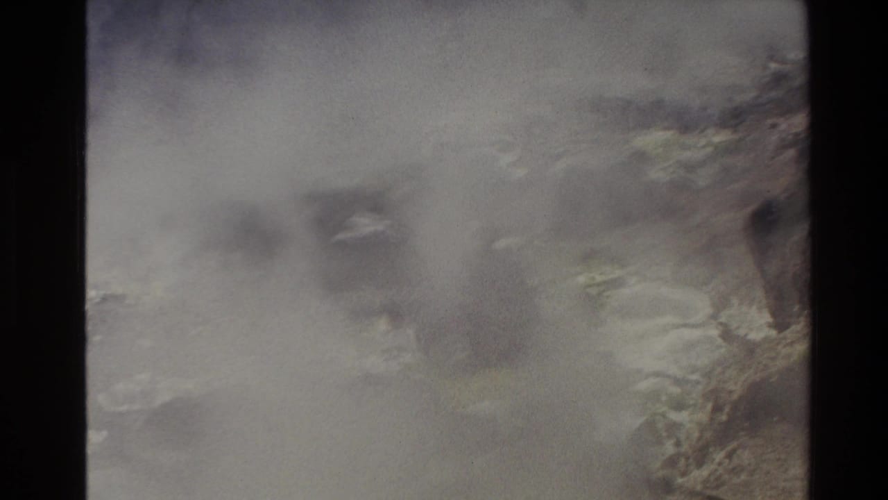 1981 New Zealand 8mm frame showing pale smoke or mist drifting over rugged mountain terrain with muted vegetation.