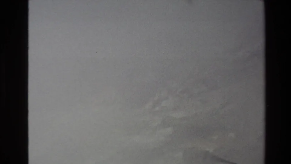 1981 New Zealand 8mm frame showing a subdued, mist-covered landscape with faint landforms and visible film grain.