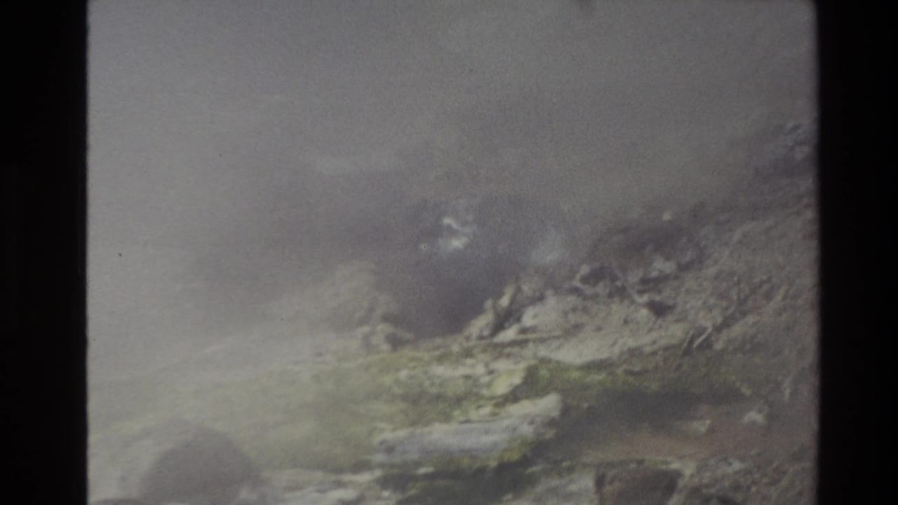 1981 New Zealand 8mm frame showing steam over rocky geothermal terrain with muted mineral colors and soft exposure.