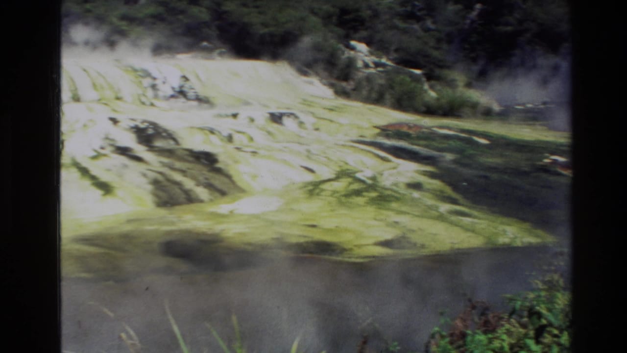 1981 New Zealand 8mm frame showing pale terraced rock or mineral formations with steam or mist and surrounding greenery.