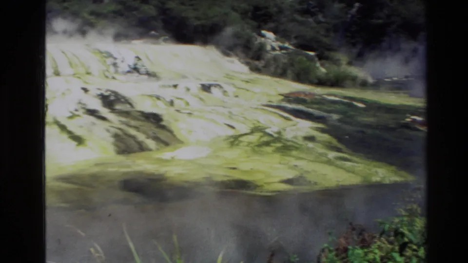 1981 New Zealand 8mm frame showing pale terraced rock or mineral formations with steam or mist and surrounding greenery.