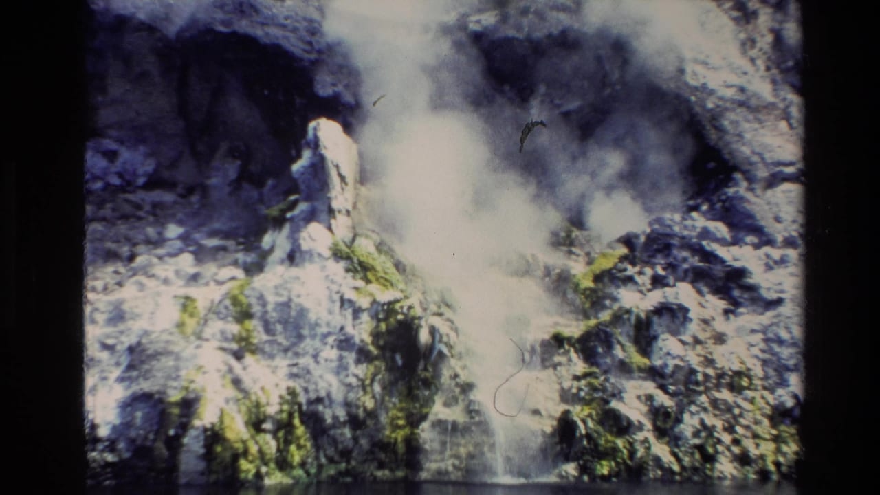 1981 New Zealand 8mm travel frame showing a close view of steam rising from rocky geothermal ground beside calm water.