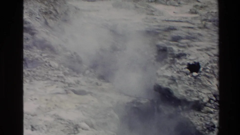 New Zealand 1981 8mm frame with dense steam billowing from a pale geothermal surface and rough dark-edged rock formations.