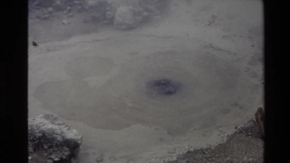 A steaming mineral pool bubbles in a rocky New Zealand landscape in 1981 8mm home-movie footage.