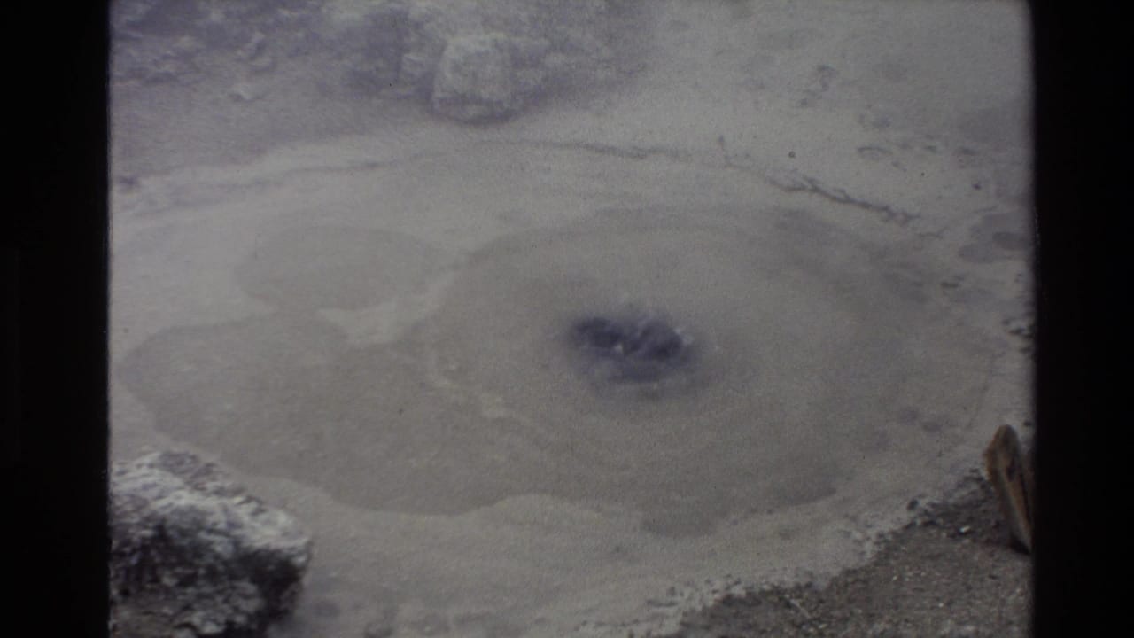 1981 New Zealand 8mm frame showing a bubbling geothermal mud pool in a pale, steamy basin.