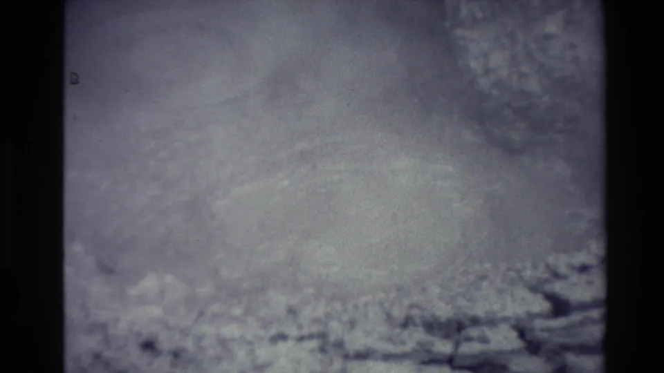 1981 New Zealand 8mm frame showing a steam-obscured geothermal mud pool, pale mineral ground, and soft home-movie film texture.
