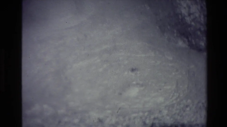Faded 8mm frame from the New Zealand geothermal clip showing an indistinct dark surface with pale steam or mineral haze.