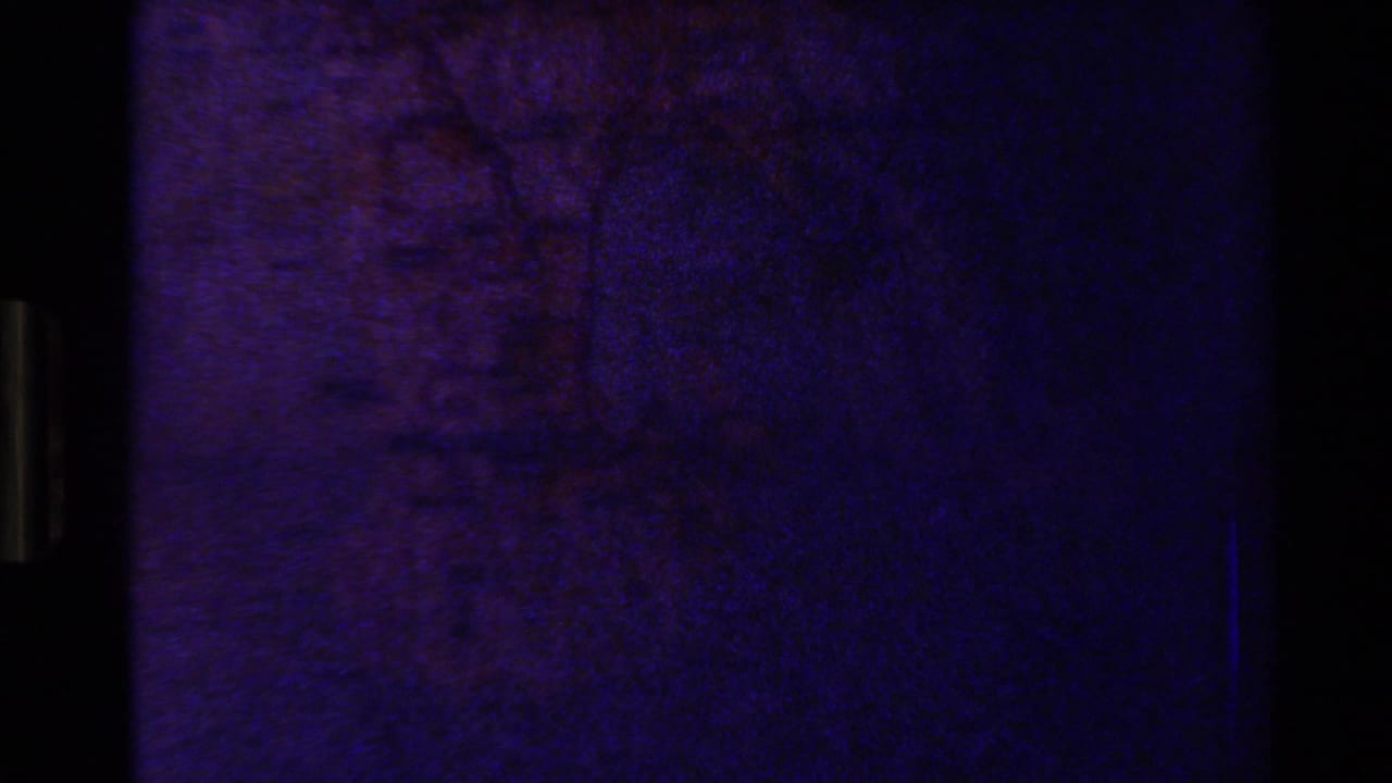 Mostly dark projected frame with faint purple map texture and black film borders.