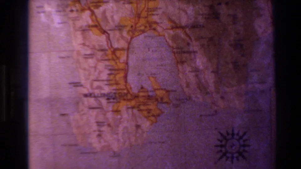 Later frame of the 1981 New Zealand map projection, with compass rose, faint labels, and dark film-edge shadows visible.