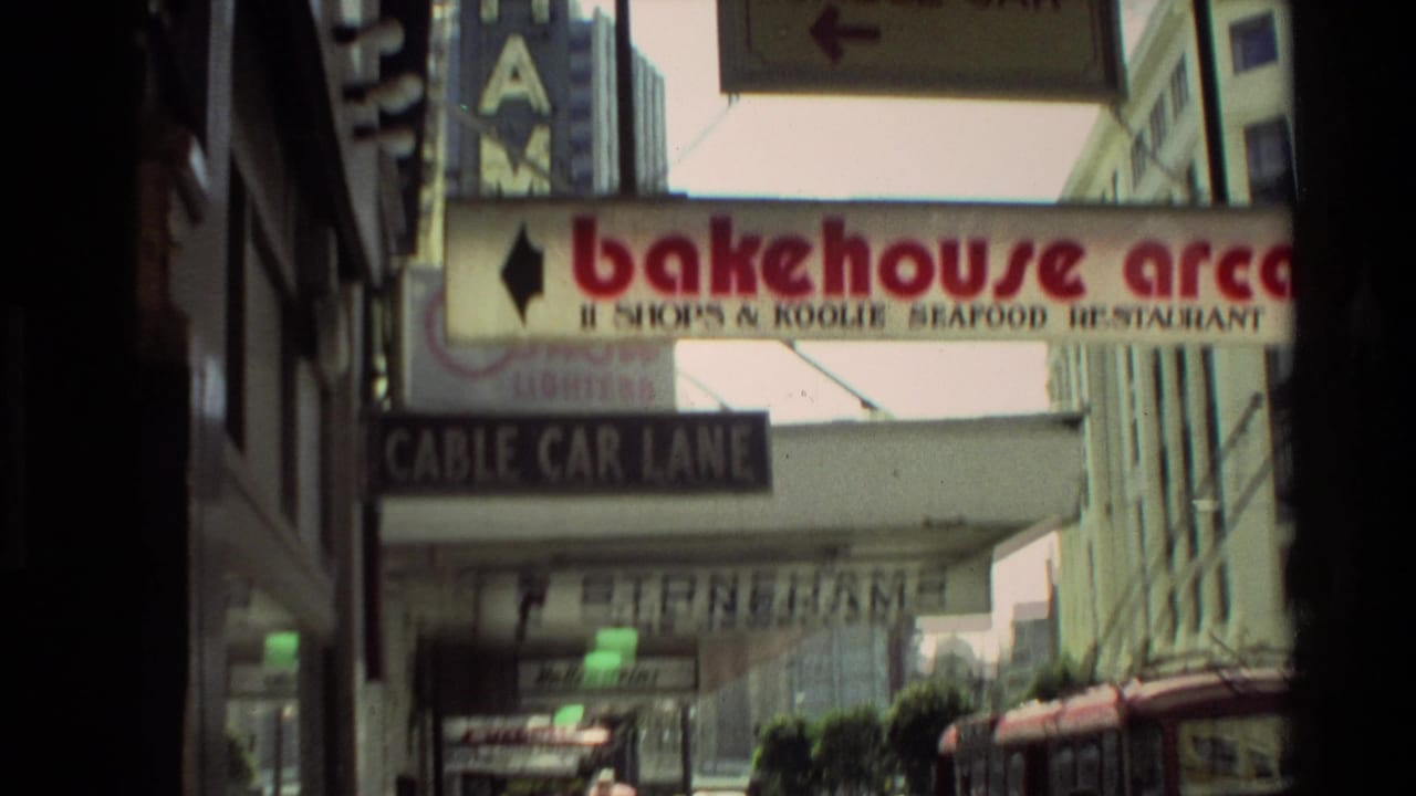 Urban street signs including Cable Car Lane and Bakehouse Arcade above a sidewalk.