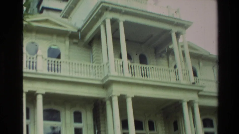 1981 New Zealand home-movie view of an ornate pale historic building with tall columns, balustrades, and arched windows.