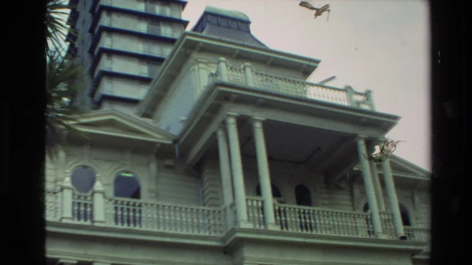 1981 New Zealand 8mm frame showing a columned historic building with arched windows and a taller building rising behind it.
