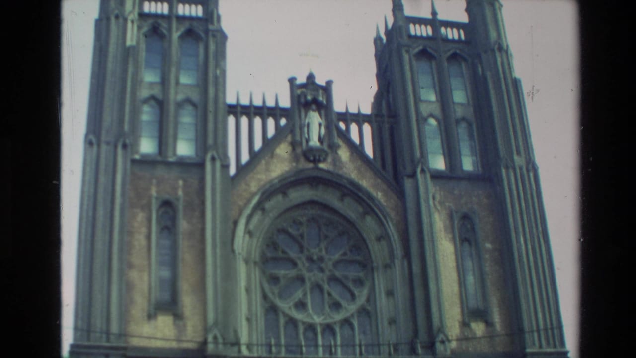1981 New Zealand home-movie frame showing a tall church-like facade with pointed towers and a large circular window.